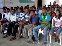 A group of people watch a presentation.