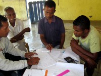 People gathered around a table, with pens, paper and calculators.