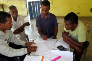 People gathered around a table, with pens, paper and calculators.