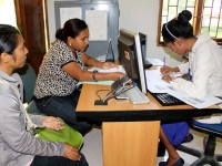 Three women sit at a computer.