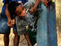 A boy drinks water from a tap
