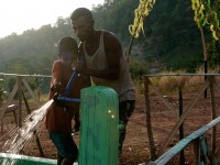 A man and child adjust a water tap.