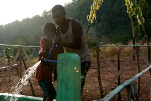 A man and child adjust a water tap.