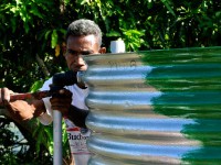 A man adjusts a pipe on a water tank.