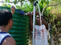 Two men tighten the pipe on a water tank.