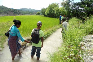 A woman measures the length of a water canal.