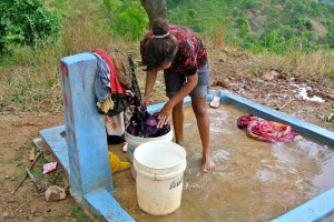 A local woman washes clothes at one of the new water taps.