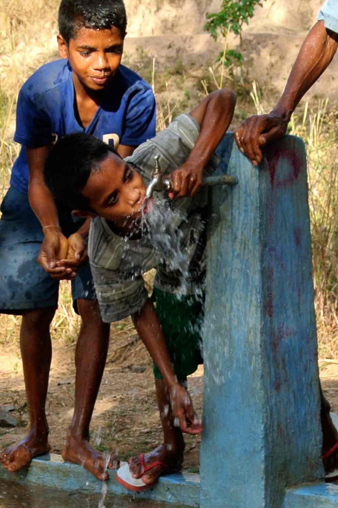 Two boys drink water from a new water tap