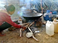 A women cooks in food over the fire, inside a traditional house.