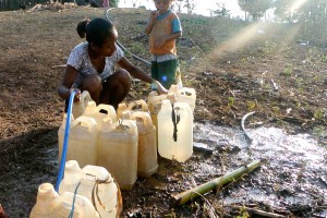 A woman fills bottles with water to be used in cooking.