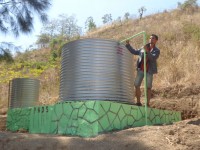 A man stands next to a water tanks