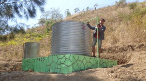 A man stands next to a water tanks