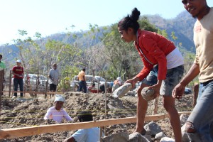 A women helps with the construction of a community center in Oecusse district. 