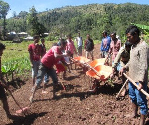Community members fill wheelbarrows with dirt.